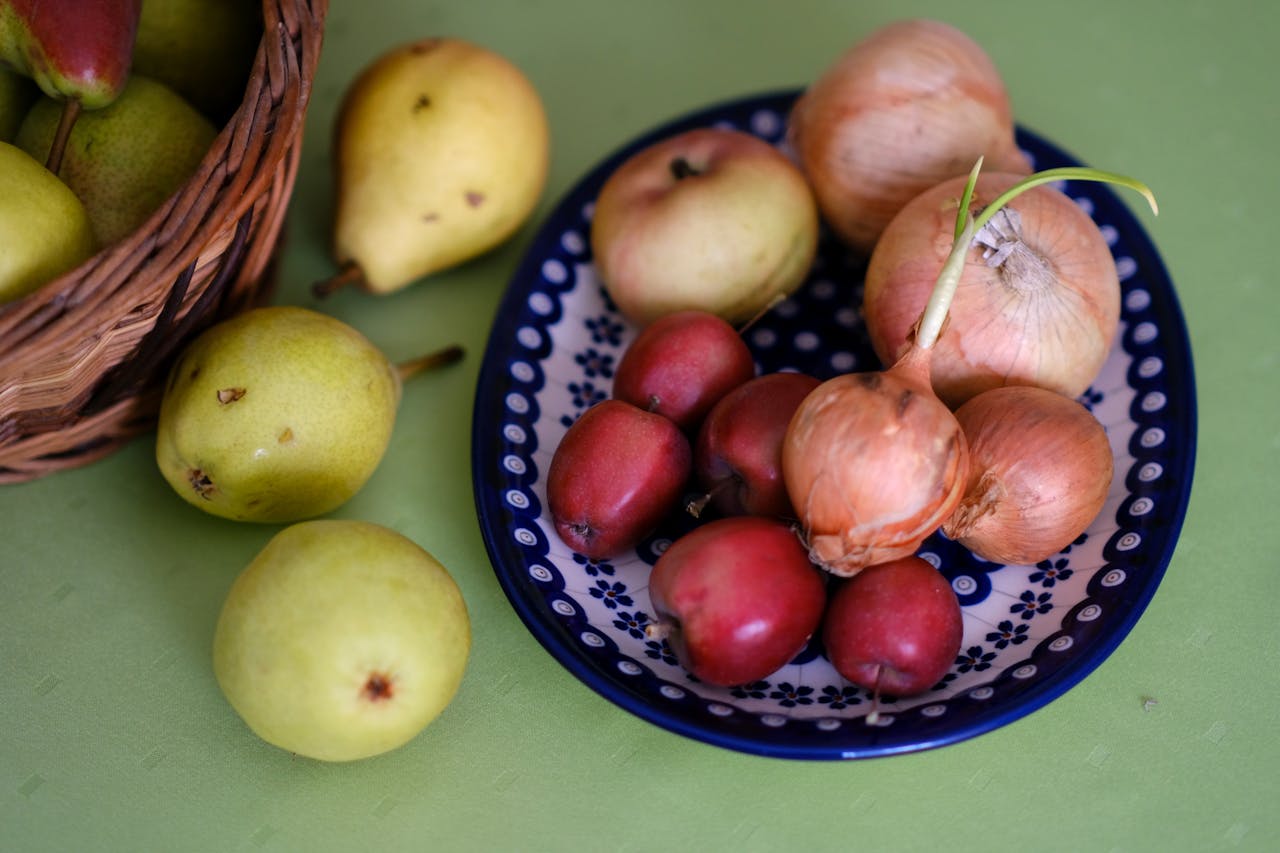 Assorted fresh fruits and onions on a decorative plate. Perfect for healthy lifestyle and food photography.